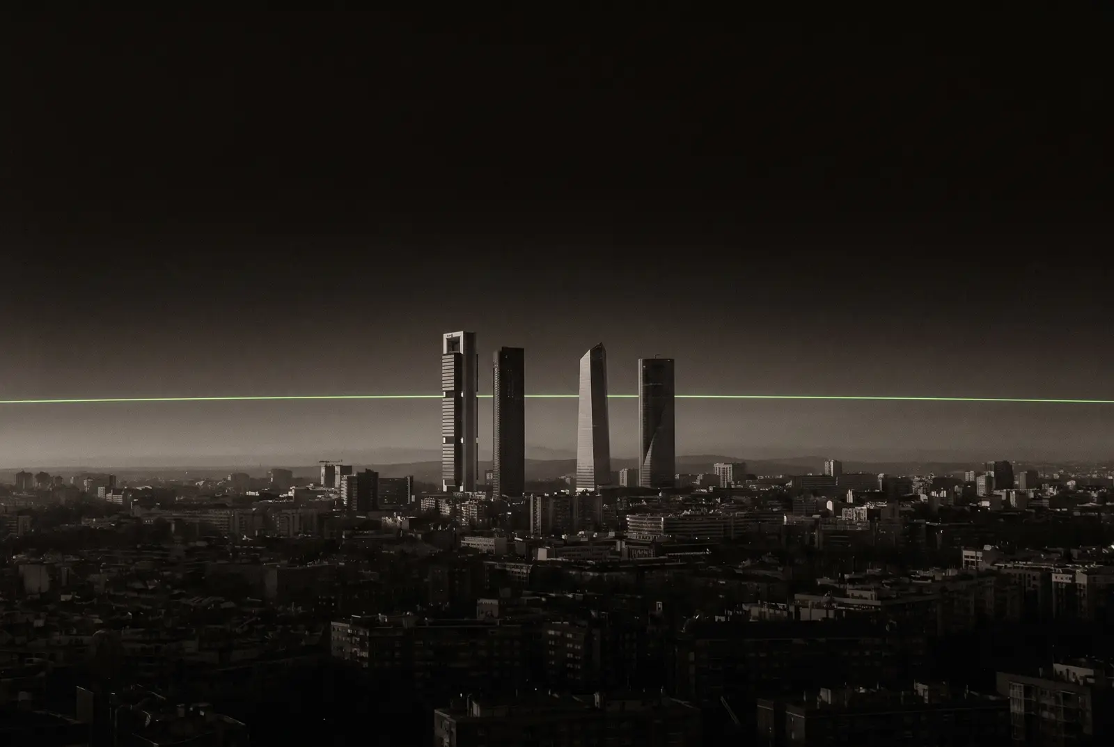 Las Cuatro Torres de Madrid recortadas sobre la ciudad de noche con una linea lima en el horizonte