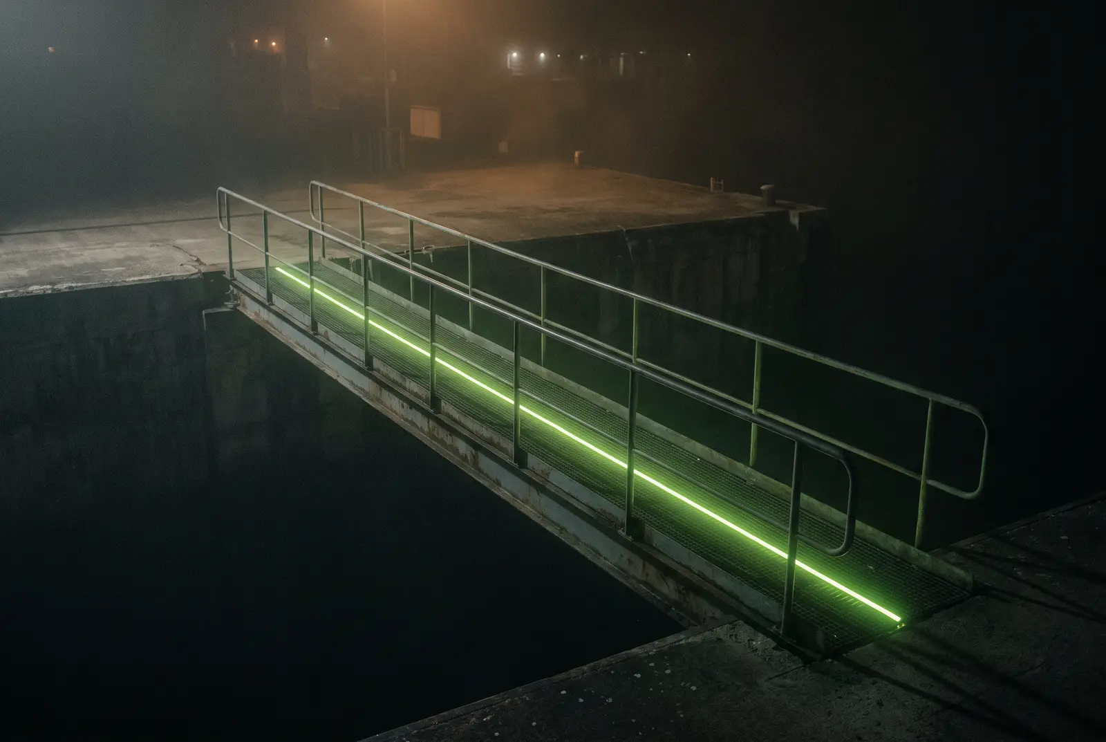 Pasarela metalica cruzando un vacio de noche con una linea de luz lima